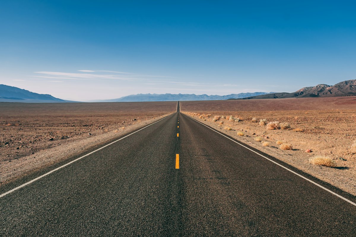 A straight desert road leading toward distant mountains