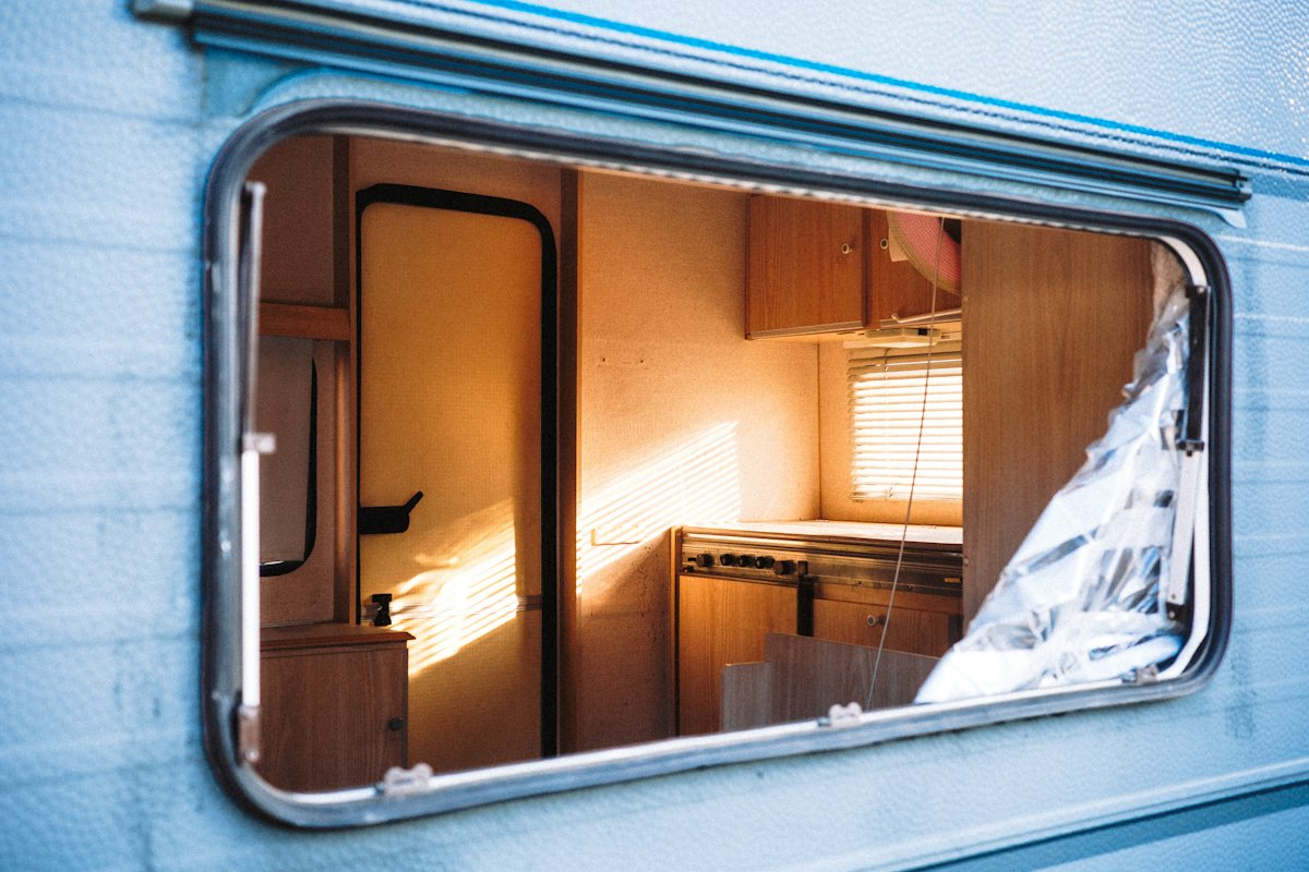 A motorhome interior with a dining table, seating and storage cupboards