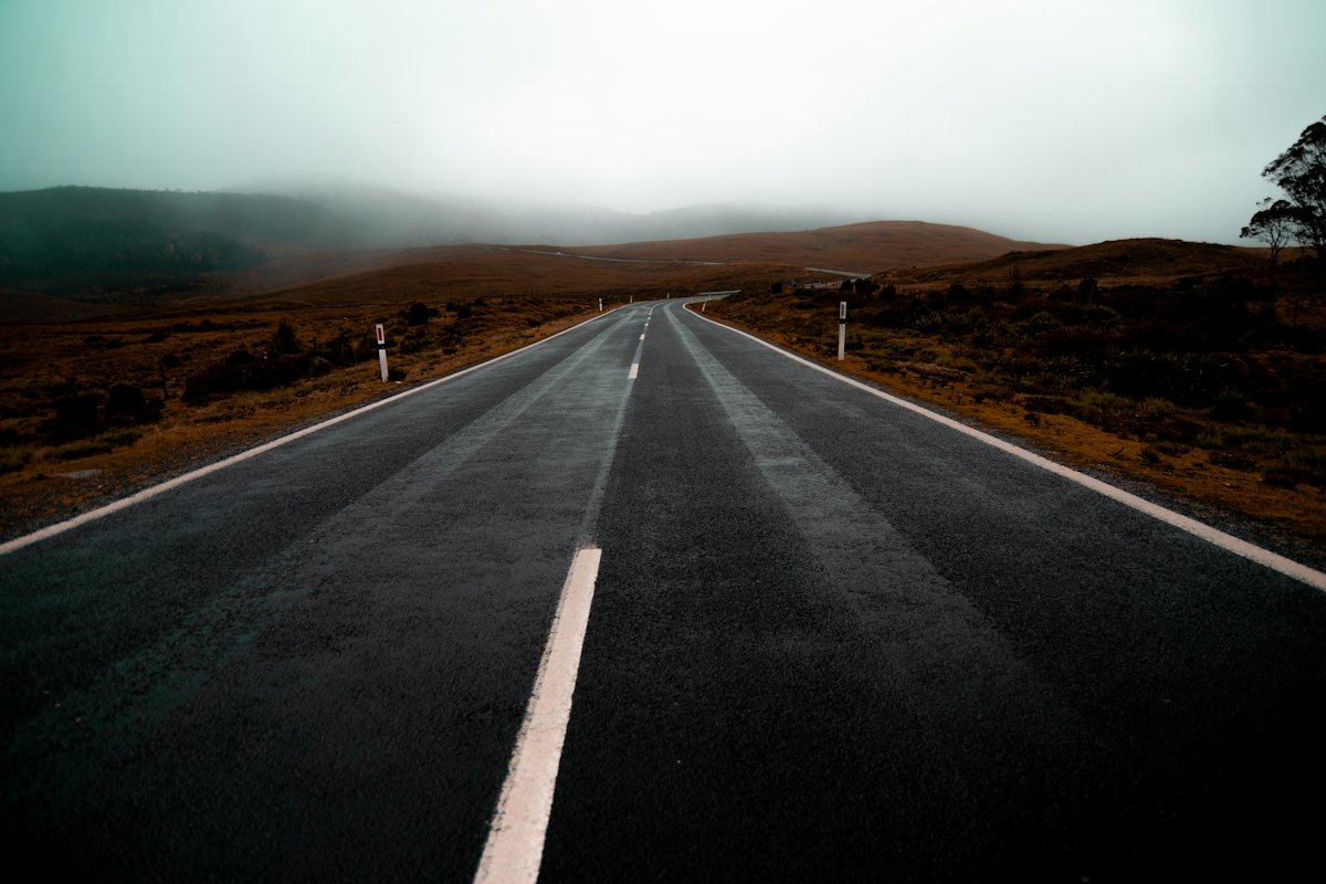An empty road through hills under a dark sky in Tasmania
