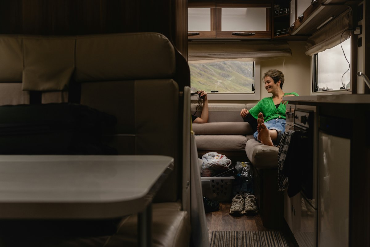 A compact campervan interior with a bed, cupboards and a small kitchen