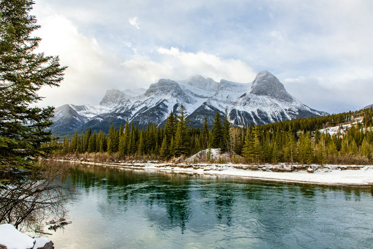 A mountain lake below rocky peaks and pine forest in Banff National Park