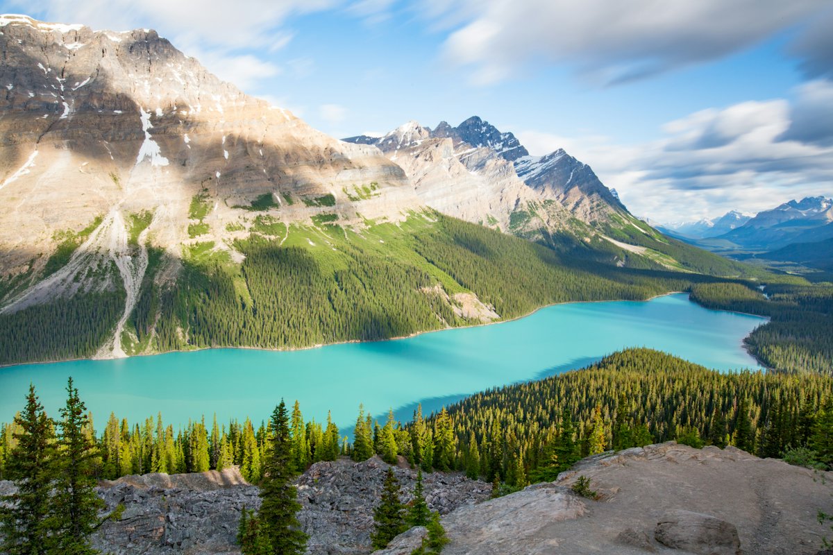 A turquoise glacial lake in a forested valley surrounded by mountains