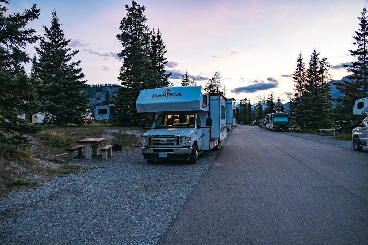 A motorhome parked at a forested campground site in Banff