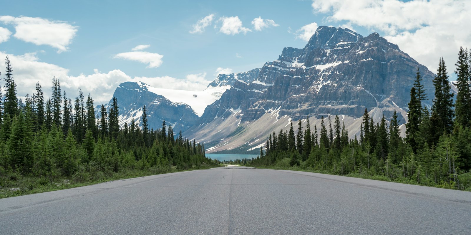 A two-lane highway running toward snow-capped peaks near Jasper, Canada