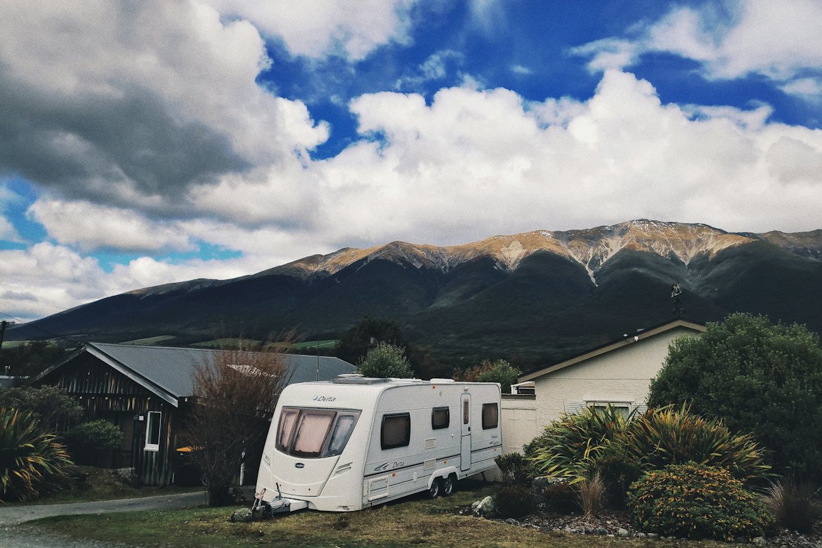 A caravan parked at a campground below green hills in New Zealand