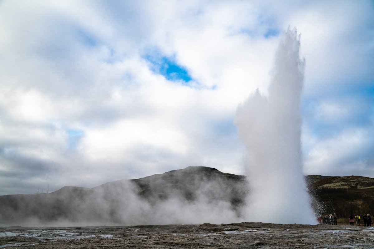 The Strokkur geyser erupting in a column of white water and steam