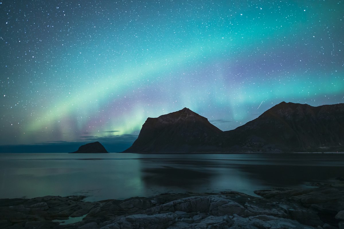 Green aurora over mountains and water in northern Norway