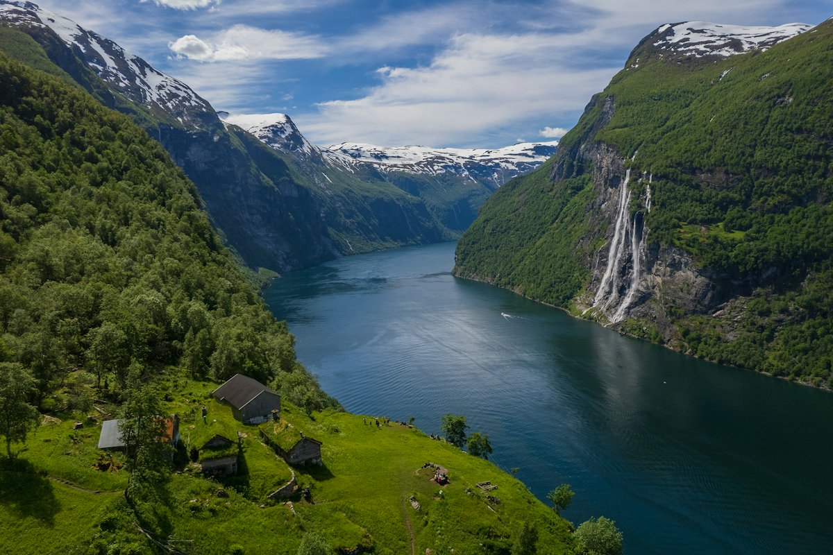 Geirangerfjord between steep green cliffs with a waterfall on the left