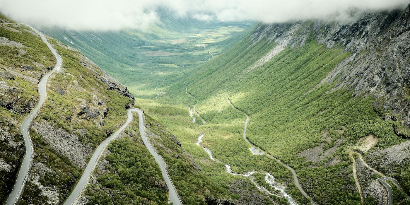 A road climbing a green valley in tight switchbacks, Norway