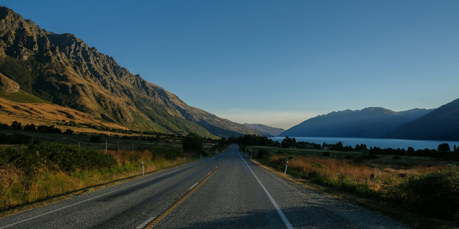 A road running beside a lake below mountains on New Zealand's South Island