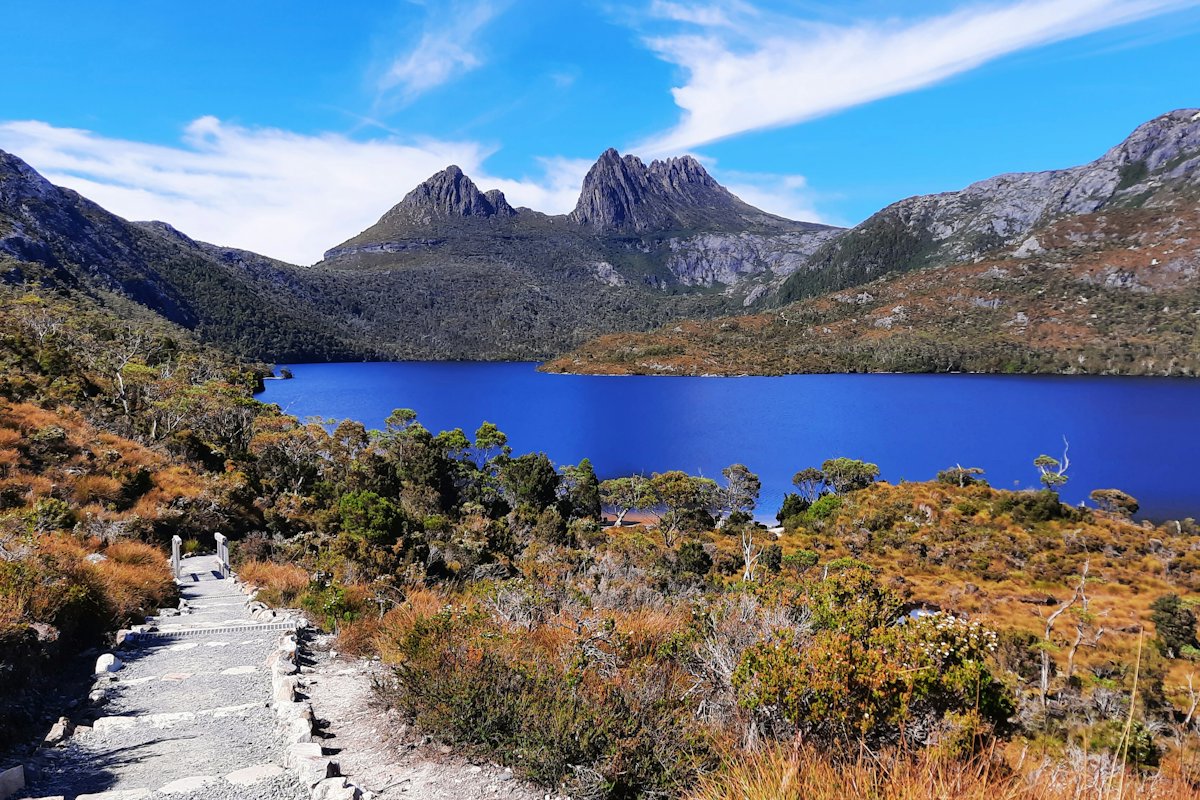 The jagged peaks of Cradle Mountain above a blue lake and a boardwalk path