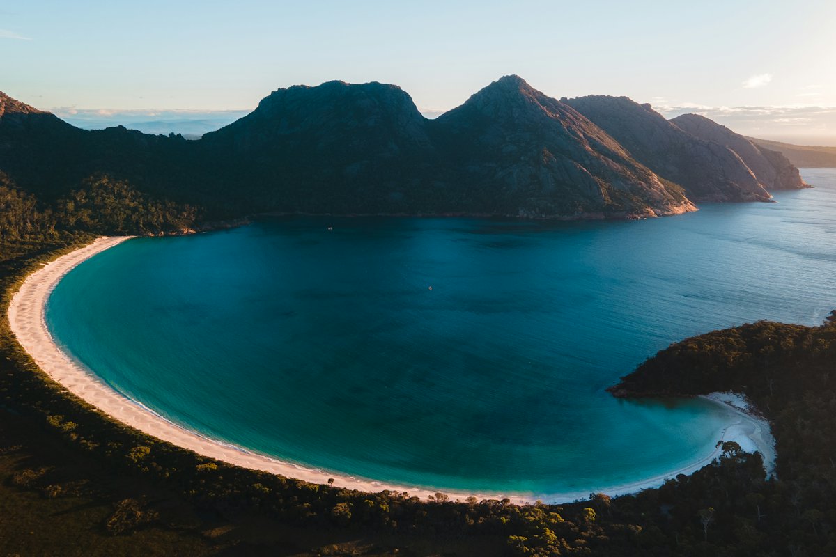 The curved white beach of Wineglass Bay seen from above, with turquoise water